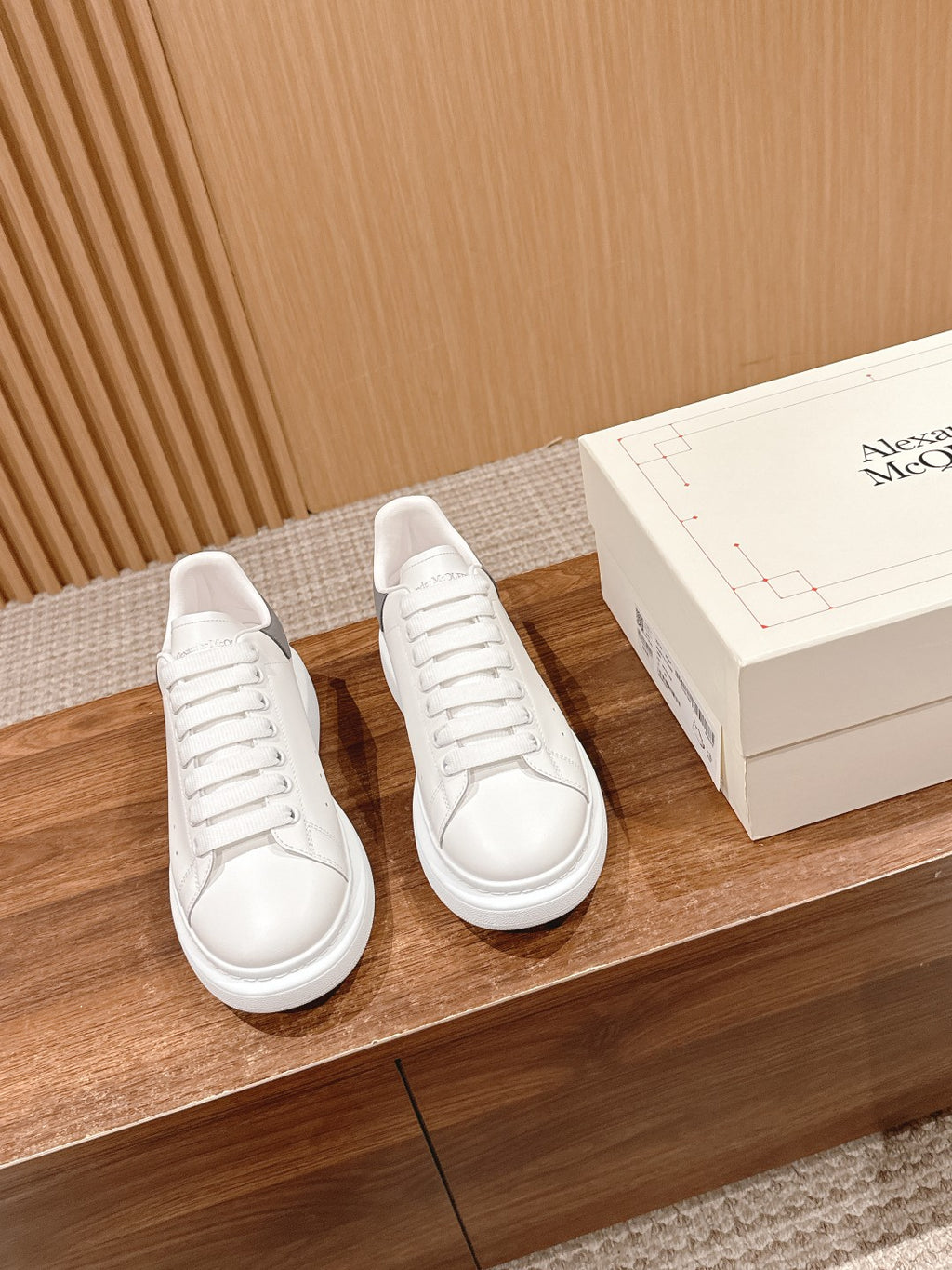 Alexander McQueen white leather sneakers on display with shoebox