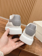 Alexander McQueen white leather sneakers with gray heel tab, held in hand