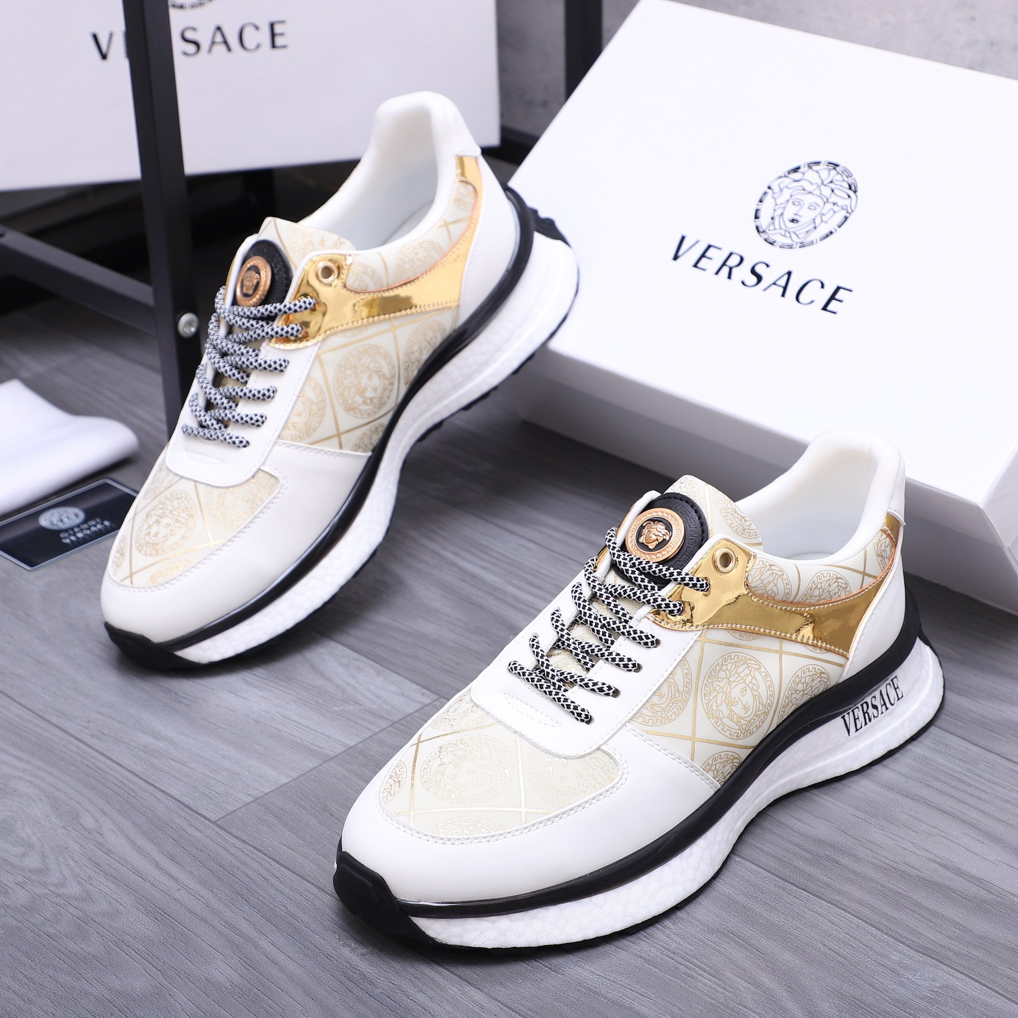 Versace sneakers with gold-accent patterned upper, white laces, and black detail sole