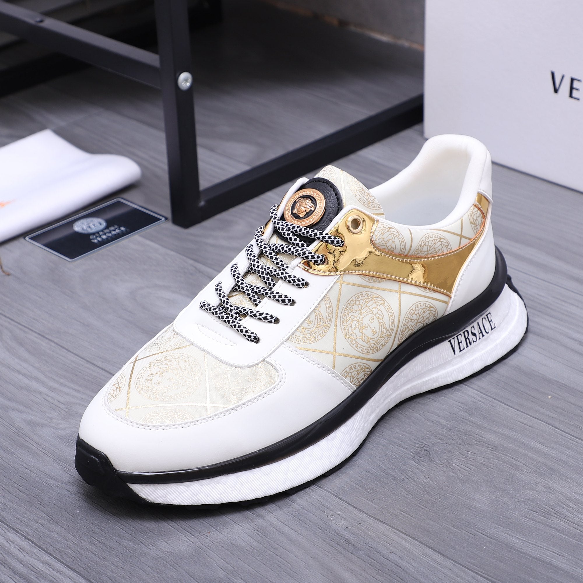 Versace white sneakers with gold patterned upper, braided laces, and textured black sole