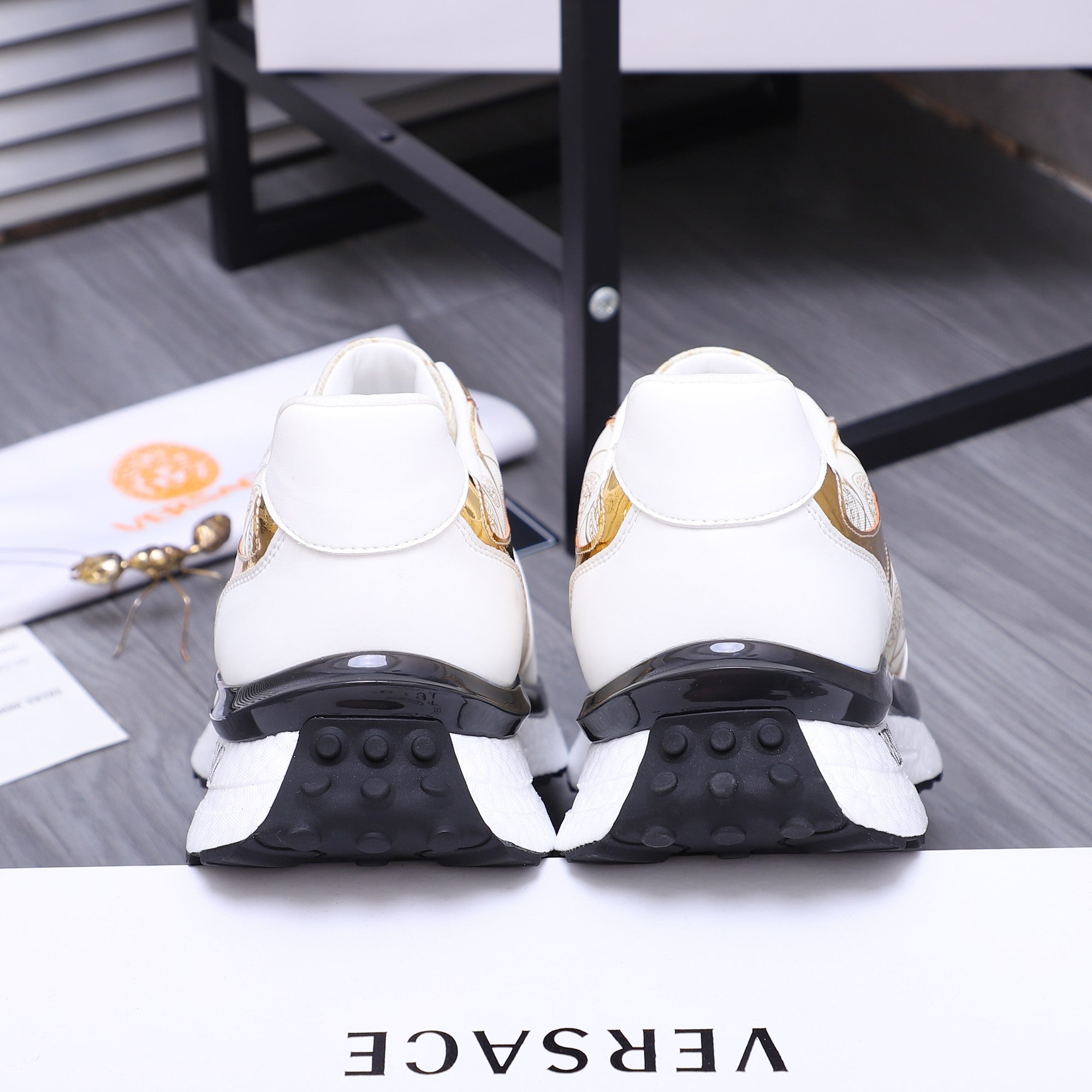 Versace sneakers with white back view and dark tread soles, showing heel profile