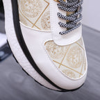 Versace sneaker close-up showing white upper, gold pattern panel, and braided laces
