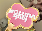 Louis Vuitton pink cow-shaped charm with "No milk" text and stitched yellow border