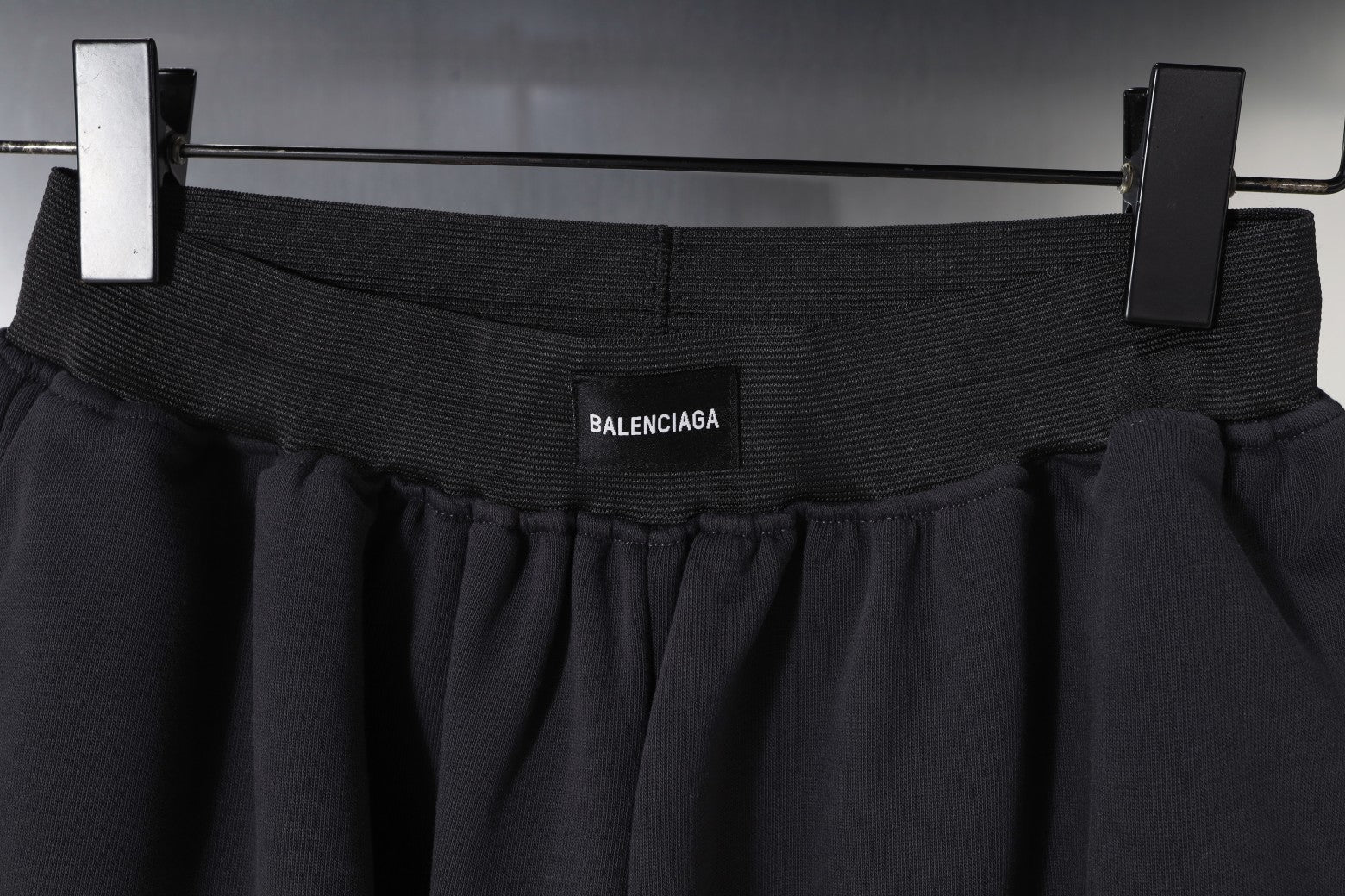 Balenciaga waistband close-up with logo, dark pleated fabric