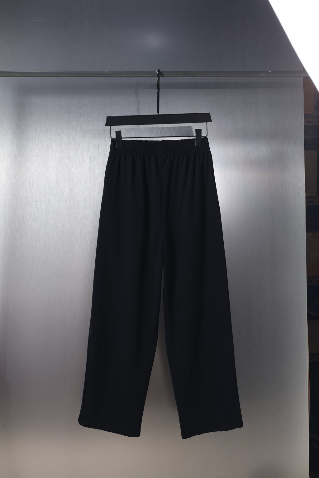 Black wide-leg pants with elastic waistband and small logo on the front thigh