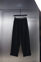 Black wide-leg pants with elastic waistband and small logo on the front thigh