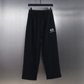 Black wide-leg pants with elastic waistband and small white Balenciaga logo print