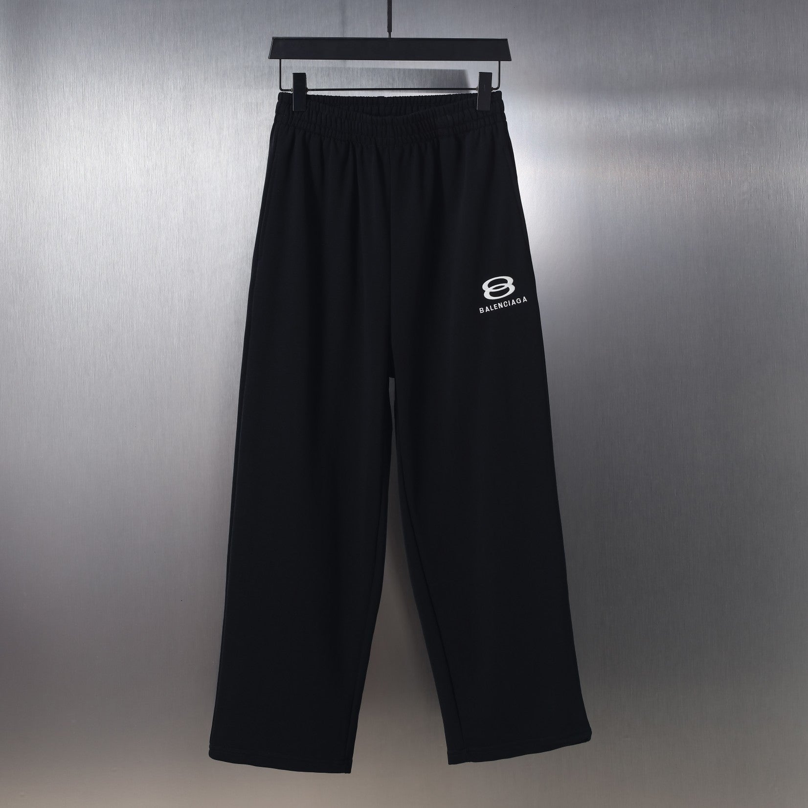 Black wide-leg pants with elastic waistband and small white Balenciaga logo print