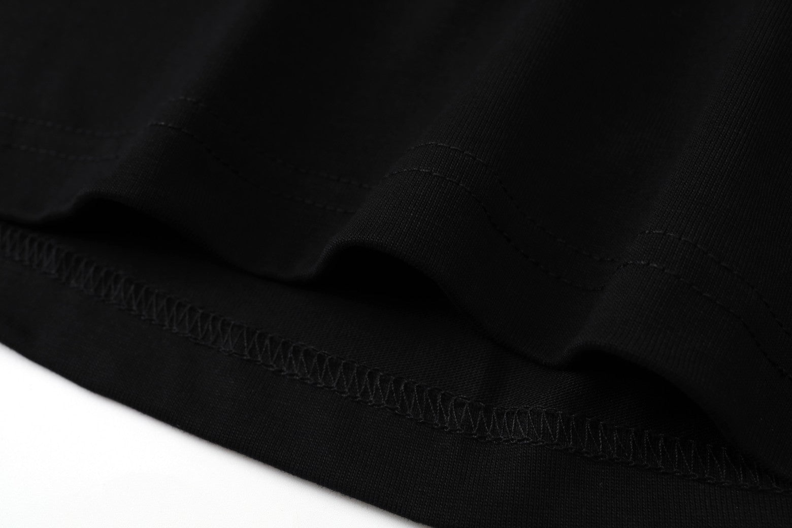 Black hem with fine stitching and gathered fabric edge
