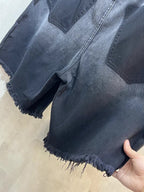 Balenciaga denim shorts, light-to-mid blue wash, distressed frayed hem, hand holding
