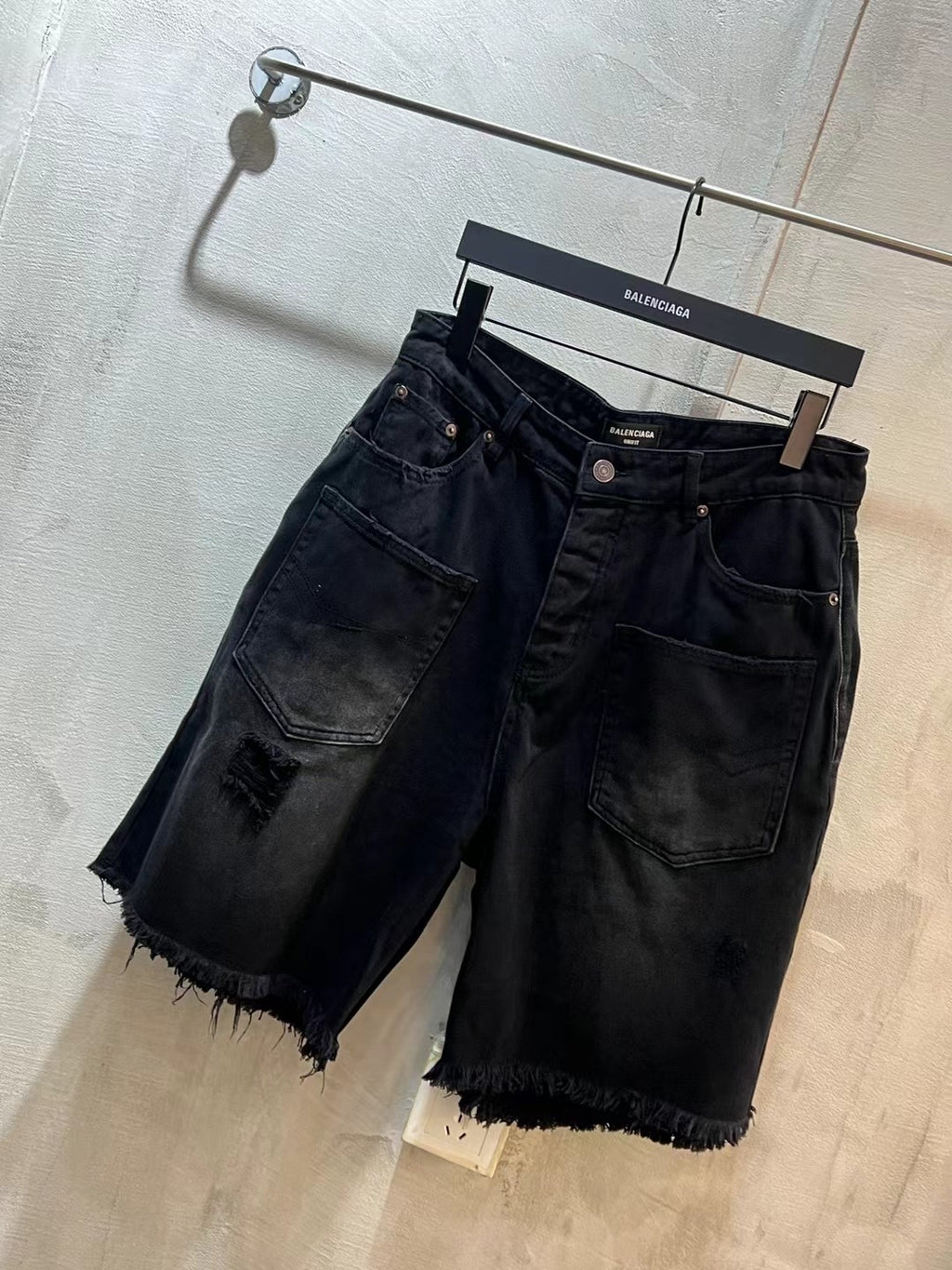 Balenciaga denim jeans shorts, dark blue, front pockets, frayed cuffs, hanger view