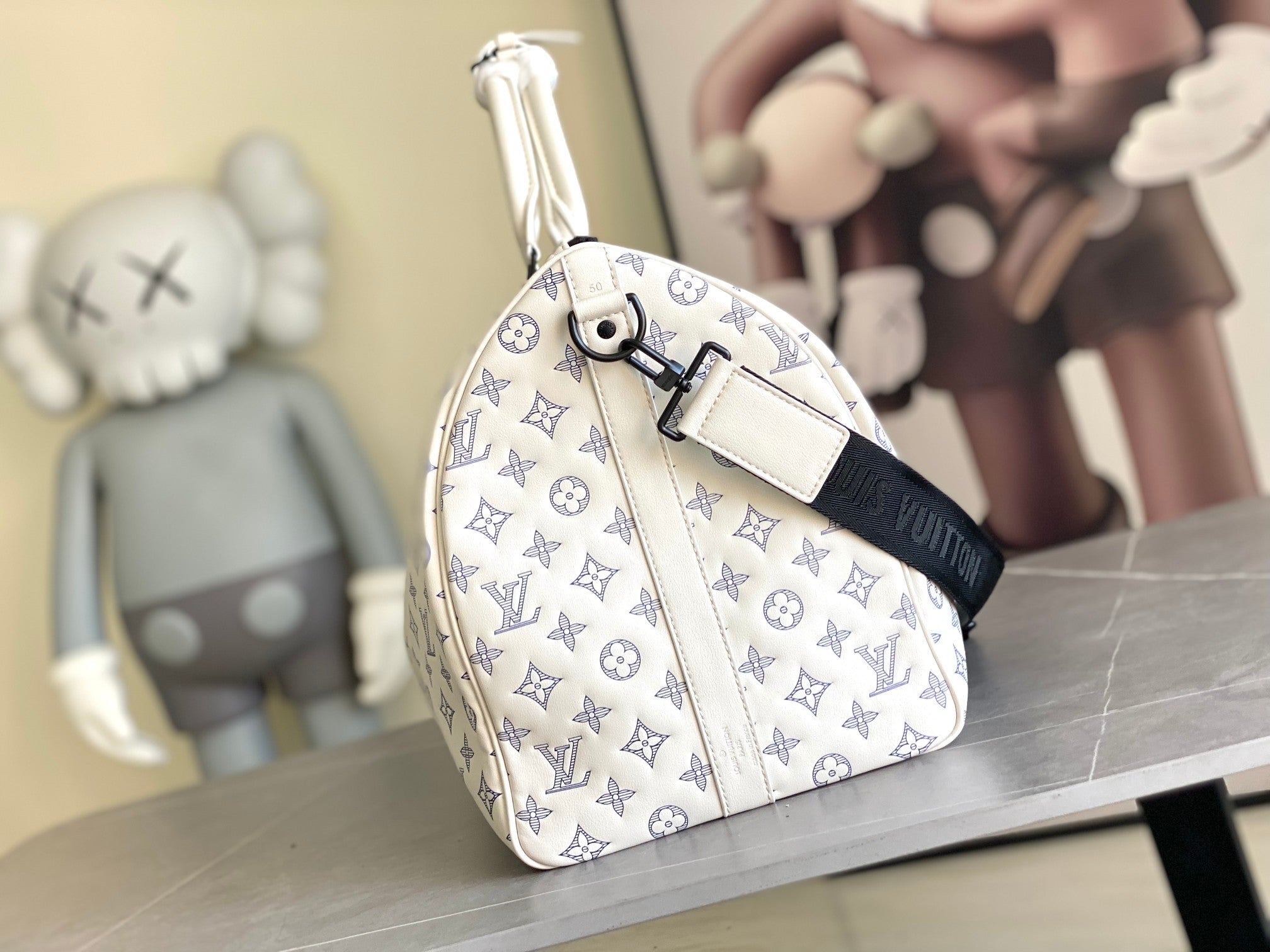 Monogram duffel bag side view with top handle and adjustable strap, blue pattern on white
