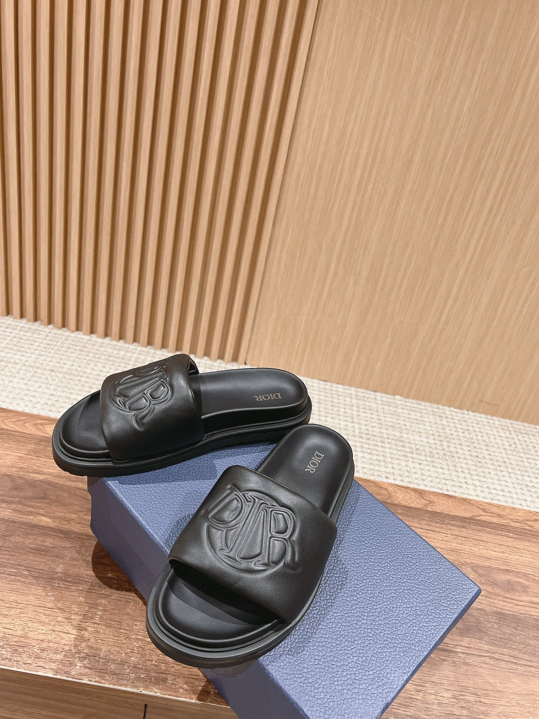 Black Dior unisex slide sandals with embossed logo, pair on shoe box