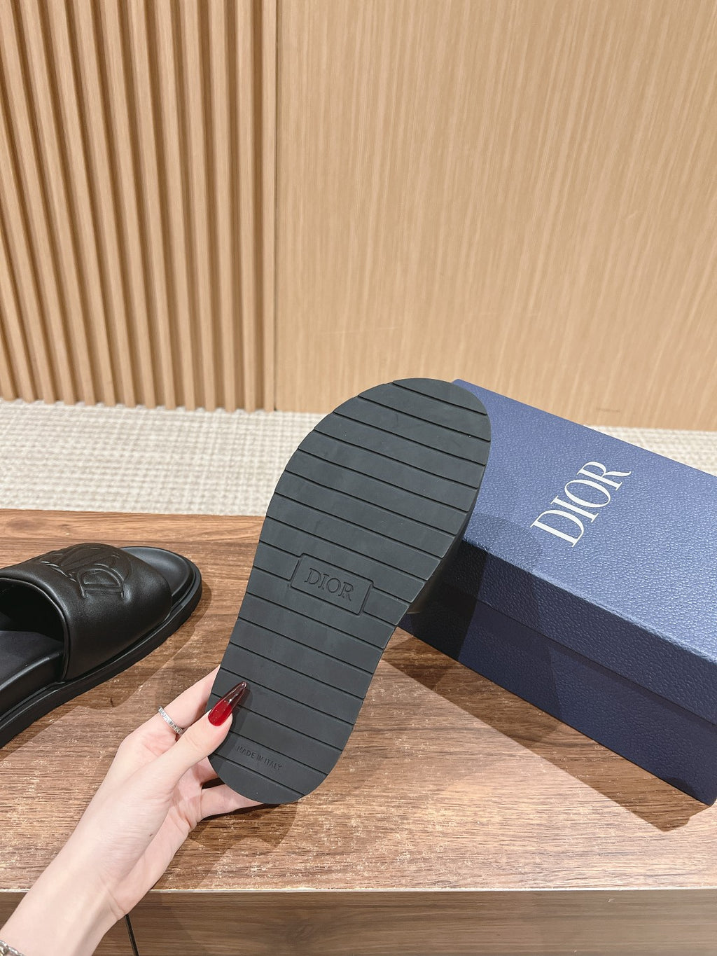 Black Dior slide sandal outsole with tread pattern, on blue box