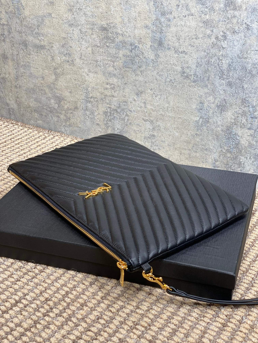 Small quilted clutch bag with YSL logo, black exterior and gold zipper pull