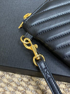 Close-up of gold-tone clasp and zipper on black small quilted bag