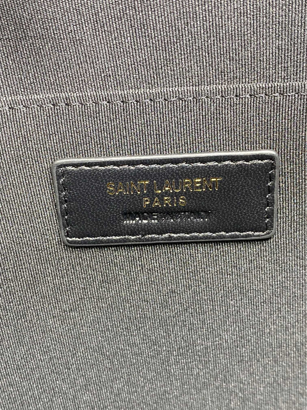 Close-up of interior label on small quilted black bag reading Saint Laurent Paris