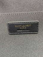Close-up of interior label on small quilted black bag reading Saint Laurent Paris