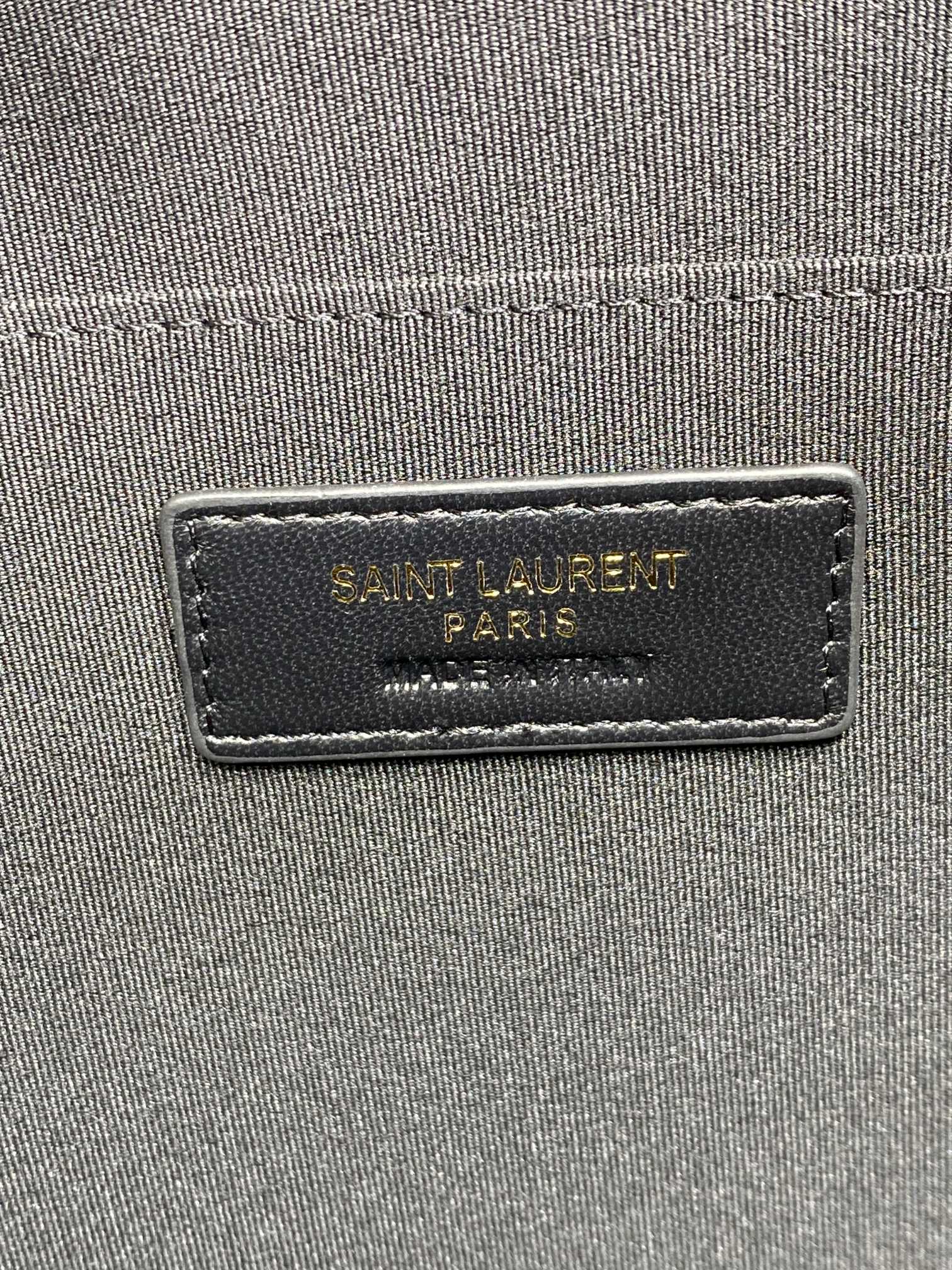 Close-up of interior label on small quilted black bag reading Saint Laurent Paris