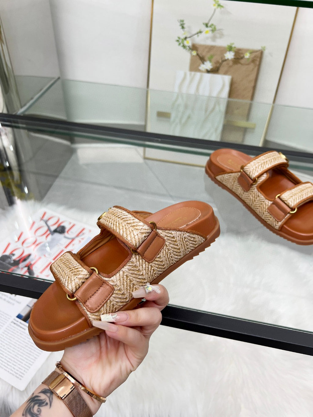 Gucci slide sandal close-up with tan textured strap, gold logo buckle, and brown footbed