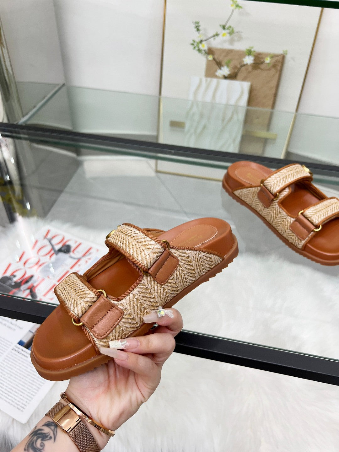 Gucci slide sandal close-up with tan textured strap, gold logo buckle, and brown footbed