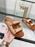 Gucci slide sandals with tan textured cross straps, gold GG buckle, and brown sole