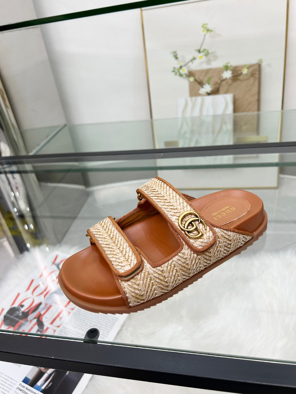Gucci slide sandal with tan textured upper and gold GG buckle on brown footbed