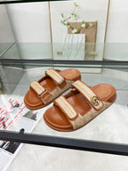 Gucci slide sandals with tan textured straps, gold GG buckle, and brown slide base