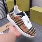 Burberry low-top sneakers held in hand, tan plaid with white laces and chunky sole