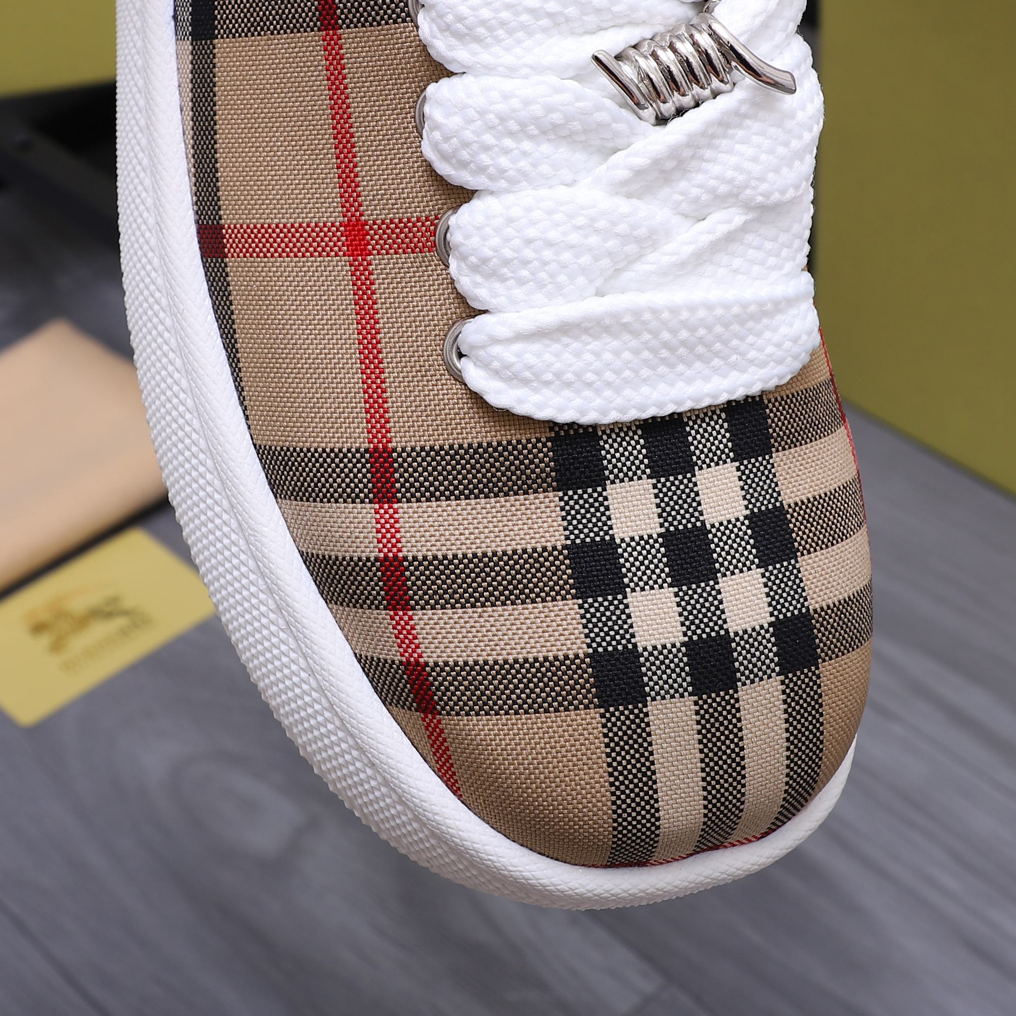 Burberry sneaker toe with tan plaid fabric, white lace, and textured white trim