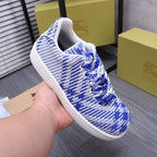 Blue and white knit lace-up sneaker being held, front and side view
