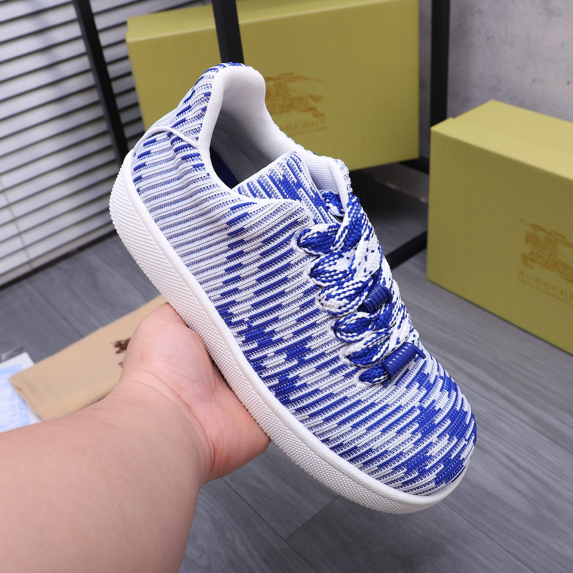 Blue and white knit lace-up sneaker being held, front and side view