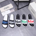 Black and white slide sandals with green logo across the strap