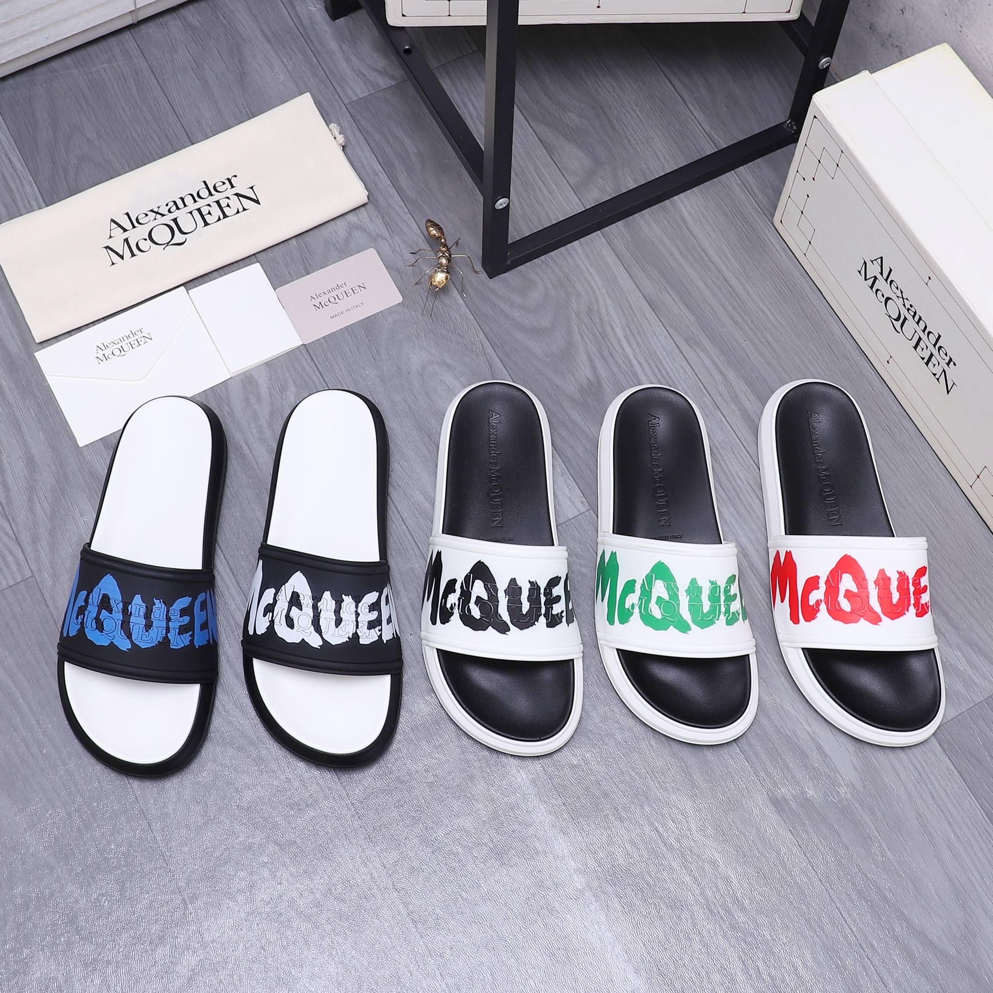 Black and white slide sandals with green logo across the strap