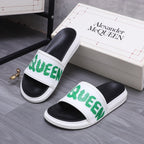 Black slide sandals with white strap and green logo, side view
