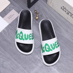 Black and white slide sandals with green logo on the front strap
