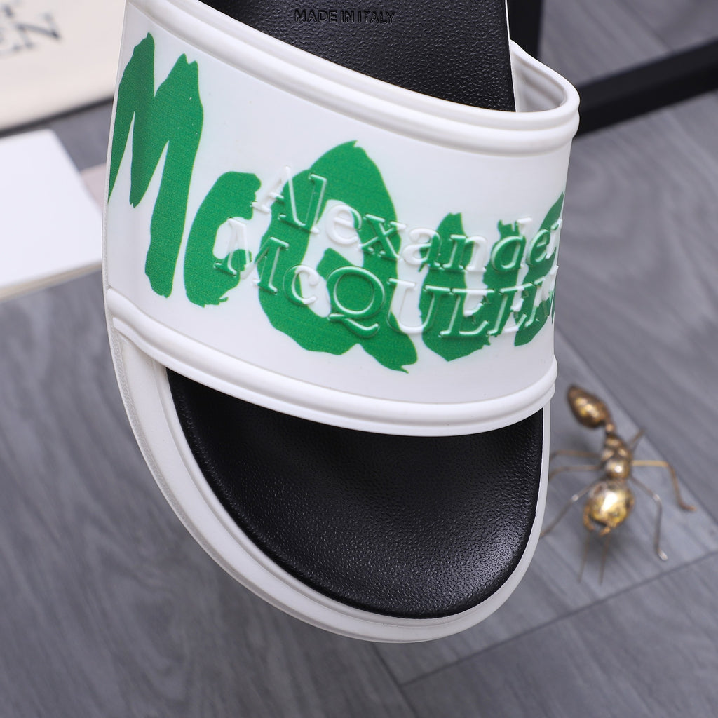 Close-up of black slide sandal strap with green logo on a white band