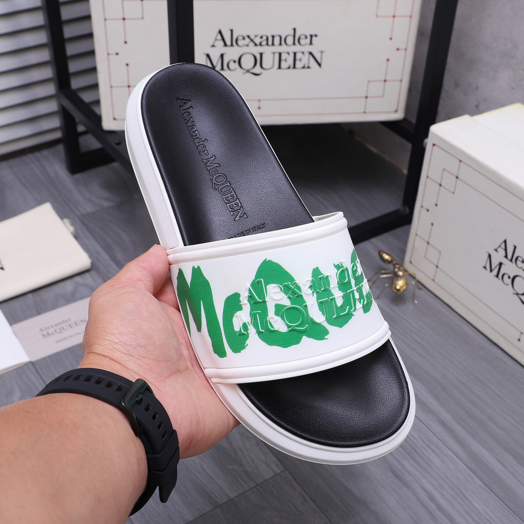 Black slide sandal with white strap and green logo, held near box