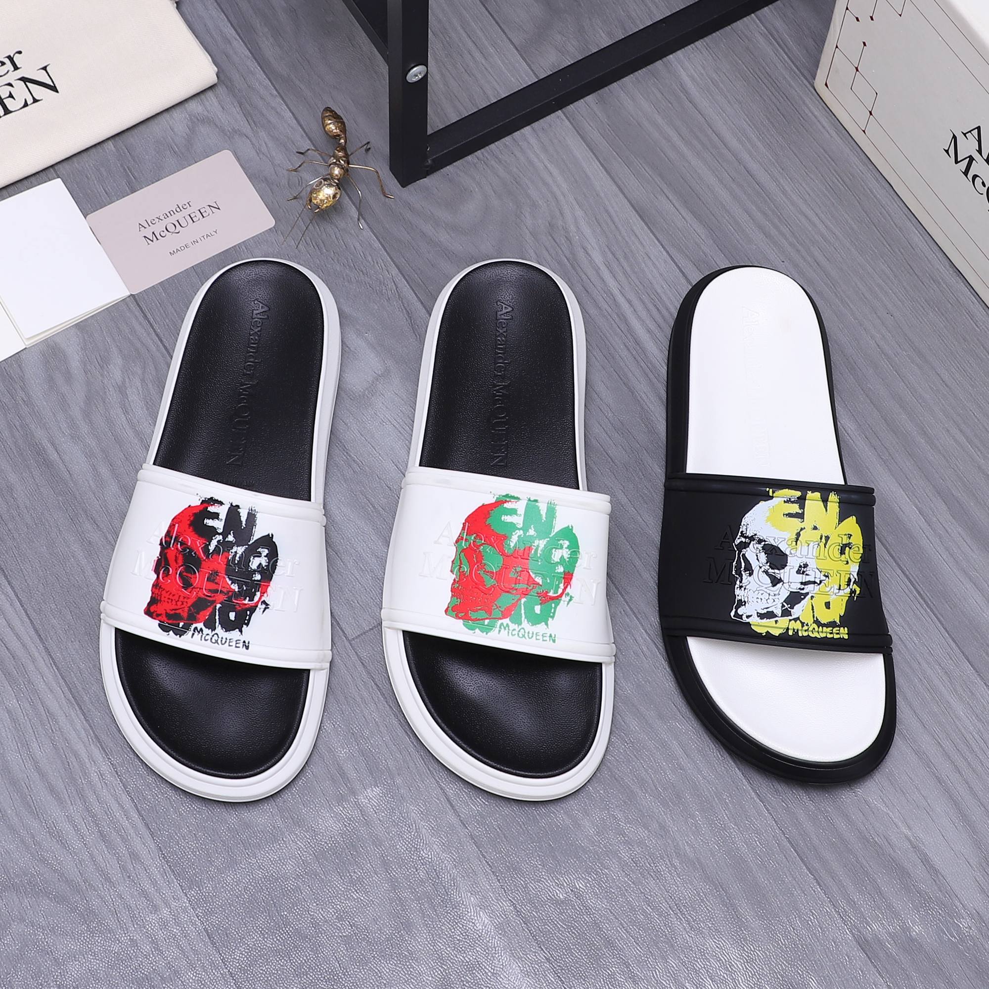 Slide sandals with white straps and colorful graphic print, black footbeds.