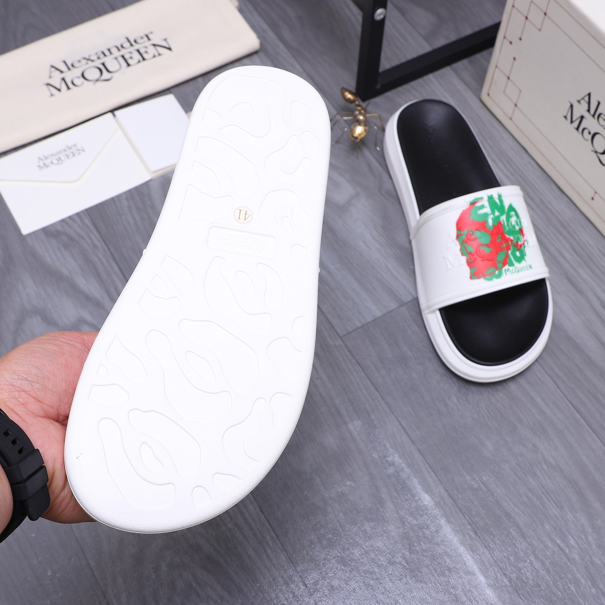 Slide sandal outsole, white rubber sole with embossed pattern, paired with black foot.