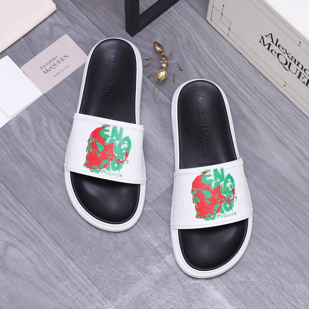 Slide sandals with white straps featuring red and green graphic print on black leather.