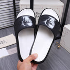 Black slide sandals with white footbed; strap shows white portrait graphic.