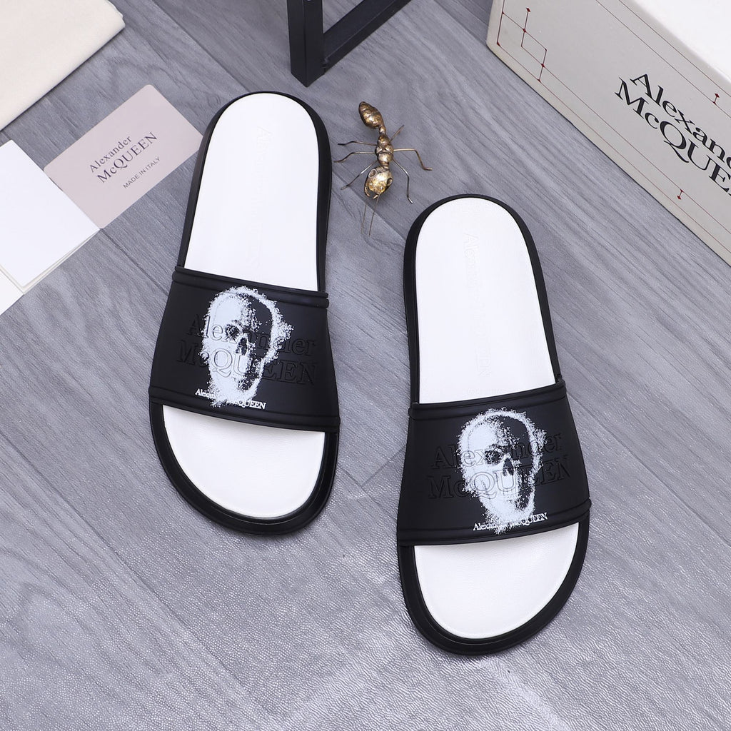 Two black-and-white slide sandals with white portrait print on straps, rounded toe.