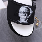 Close-up of black slide sandal strap with white portrait print and small logo text.