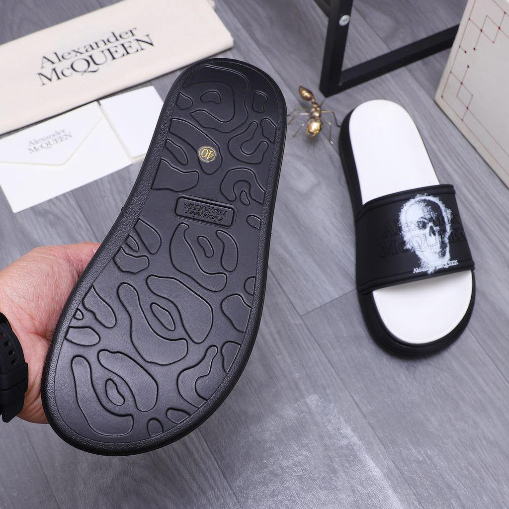Black rubber outsole of slide sandal with textured tread and small logo mark.