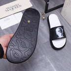 Black rubber outsole of slide sandal with textured tread and small logo mark.