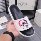Alexander McQueen slide sandal showing toe strap and red/blue skull print on white