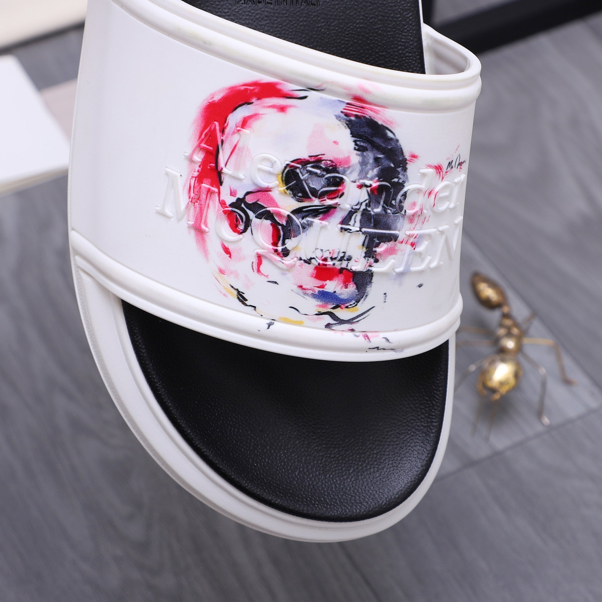 Alexander McQueen slide sandal close-up of white strap with red/blue skull print