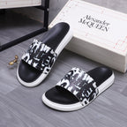 Alexander McQueen slide sandals with black upper, white graphic band, white cushioned sole