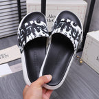 Alexander McQueen slide sandals held up: black footbed with black-and-white graphic strap